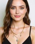 Woman wearing gold necklaces and earrings on a plain background