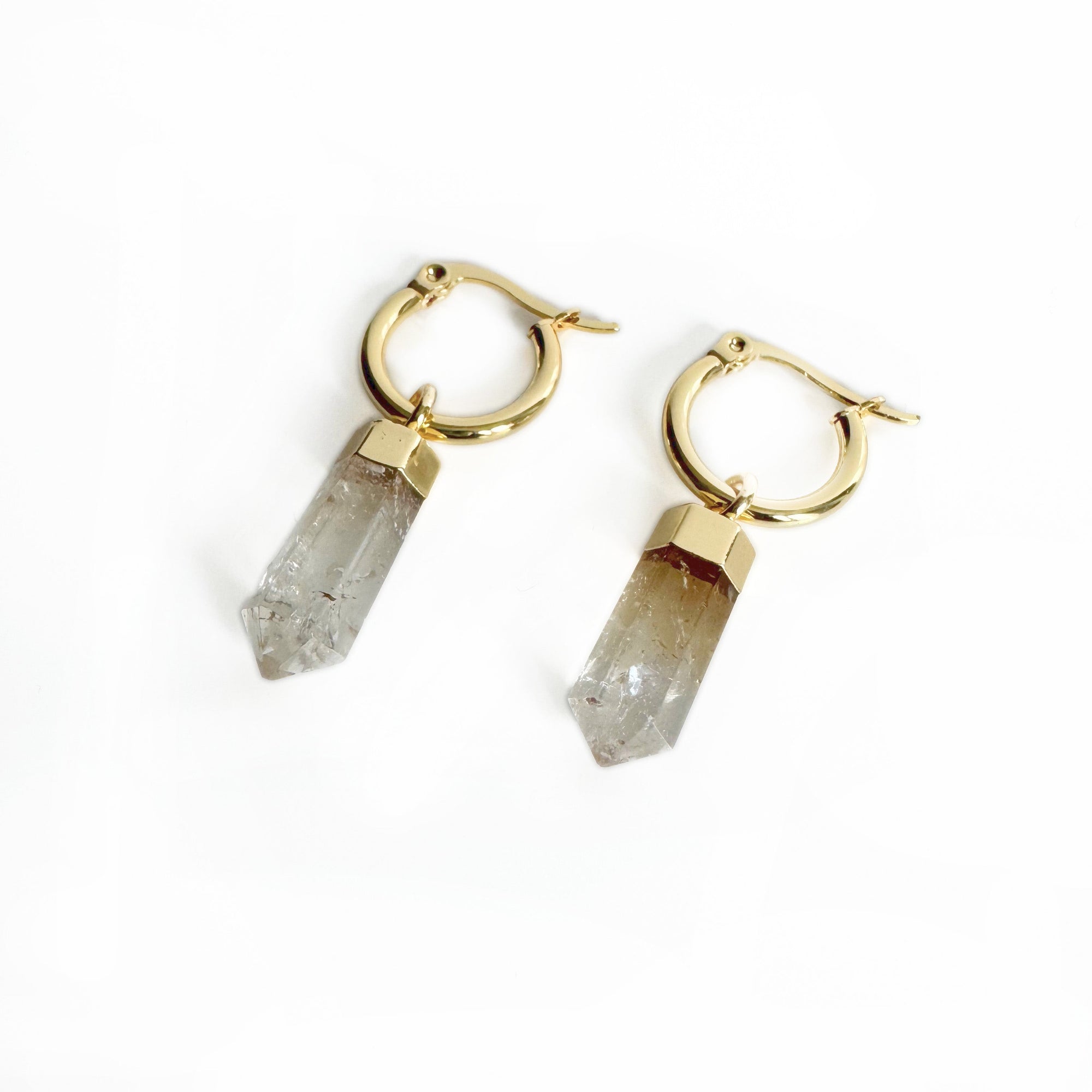 Gold hoop earrings with crystal-like pendants on a white background