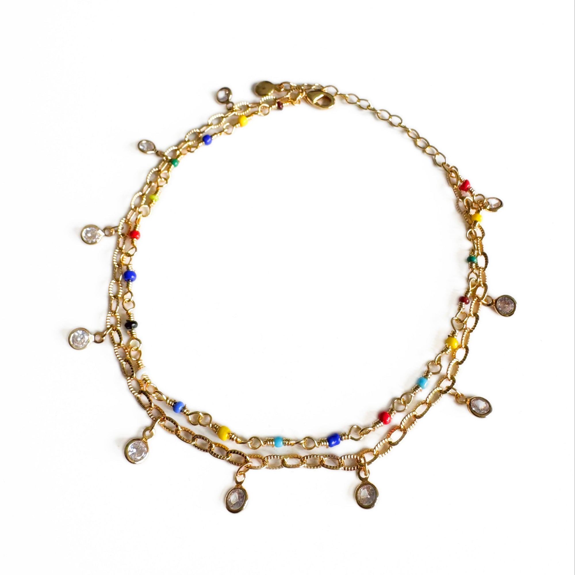 Gold anklet with colorful beads on a white background