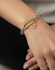 Bracelet with gold and silver charms on a wrist against a neutral background